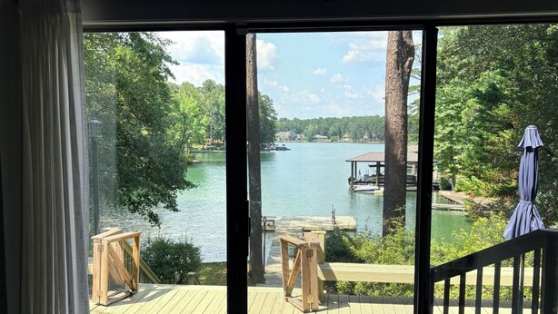 A room with a large sliding glass door leading to an outdoor deck with a view of a lake, wooden furniture, and a covered area. - Nero's Point Lake Martin  Home
Pet friendly, Great for Football Weekends (Eclectic)