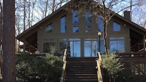 A wooden staircase leading to a modern building with large windows and a covered porch.