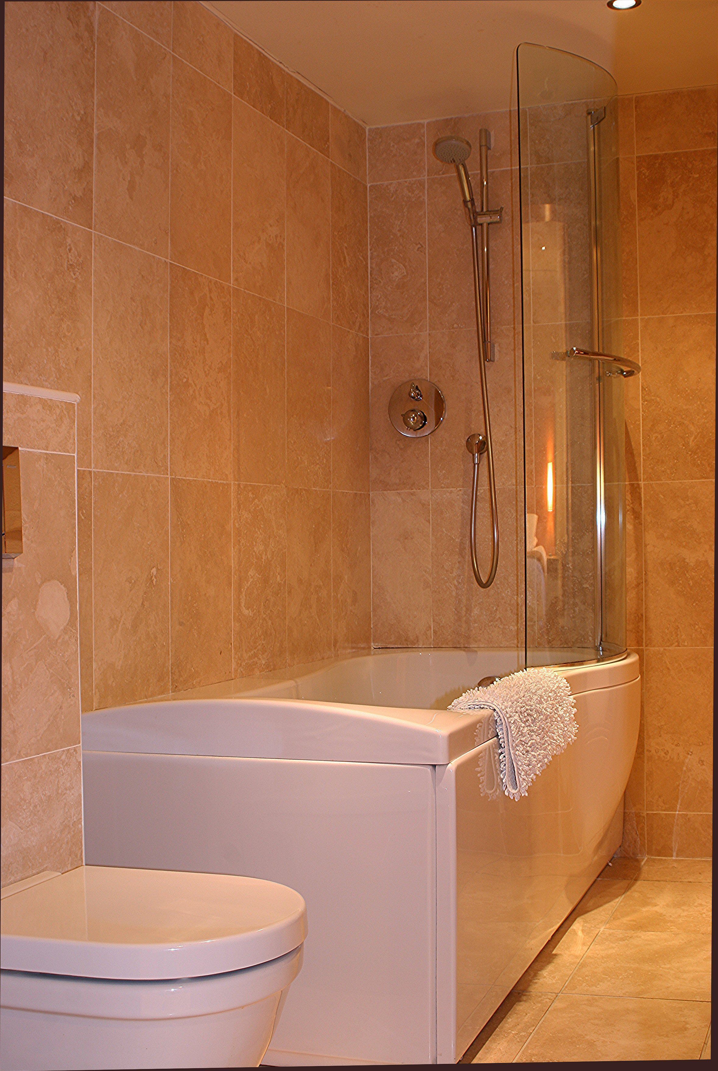 Une salle de bain avec une baignoire, une douche à parois de verre et des toilettes.