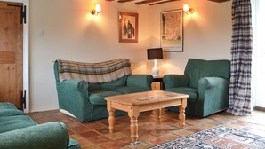 A cozy living room with two green sofas, a wooden coffee table, and a lamp. - 3 bedroom accommodation in South Acre (South Acre)