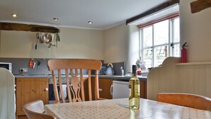 A kitchen with wooden chairs, a table with a polka dot tablecloth, and a bottle of wine on the table. - 3 bedroom accommodation in South Acre (South Acre)