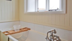 A bathroom with a bathtub, a window with a view, and a wooden tray with towels. - 3 bedroom accommodation in South Acre (South Acre)