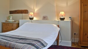 A bedroom with a bed, bedside lamps, a dresser, a nightstand, a wall-mounted shelf, and a wooden wardrobe. - 3 bedroom accommodation in South Acre (South Acre)