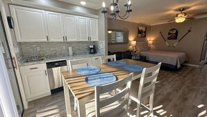 A compact kitchen with white cabinets, a dining table with blue placemats, and a ceiling fan. - Apple Valley 23 at Rumbling Bald (Lake Lure)