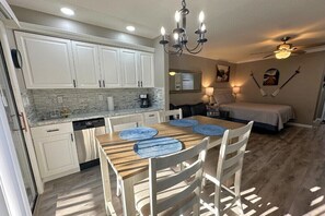 A compact kitchen with white cabinets, a dining table with blue placemats, and a ceiling fan. - Apple Valley 23 at Rumbling Bald (Lake Lure)
