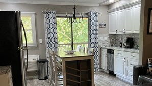 A modern kitchen with a dining area, wooden flooring, white cabinets, and a chandelier. - Apple Valley 23 at Rumbling Bald (Lake Lure)