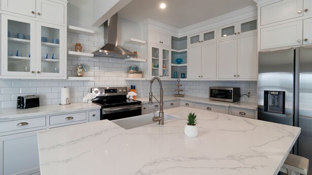 A modern kitchen with white cabinetry, a marble island, stainless steel appliances, and a built-in oven. - Remodeled Townhome • Covered Heated Pool • 2 Minute Walk to Beach (South Padre Island)
