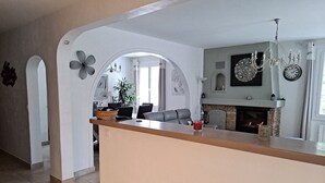Una cucina moderna con isola centrale, camino e zona pranzo con divano.
