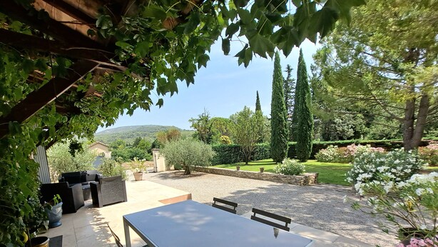 Patio esterno con tavolo e sedie, immerso nel verde e con vista sulla campagna.