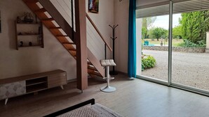 Un interno moderno con una scala in legno, una panca, un appendiabiti e vista su un giardino attraverso una porta in vetro.