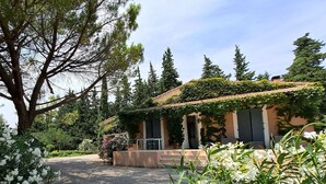 Un edificio con un portico coperto, circondato da alberi e piante fiorite.