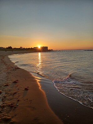 A beach at sunset with a building in the background. - Cozy Beach Home in Oceanview (Norfolk)