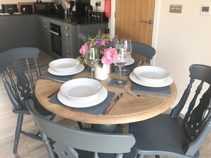 A dining table set with white plates, a vase with flowers, and a wine glass. - The Old Dairy - UK31253 (Pickering)
