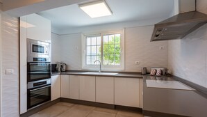 A modern kitchen with a built-in oven, a window with a view, and a stainless steel range hood.