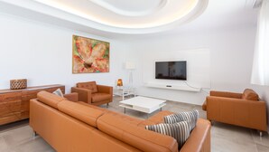 En moderne stue med en stor sofa, et sofabord og et fladskærms-tv monteret på væggen.