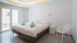 A modern bedroom with a bed, bedside tables, a chair, and a view through the door.