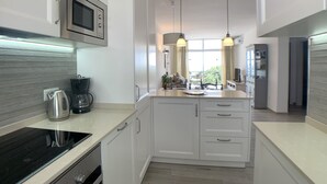 Eine moderne Küche mit weißen Schränken, einer eingebauten Mikrowelle, einer Kaffeemaschine und Pendelleuchten.