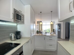 A modern kitchen with white cabinetry, a built-in microwave, a coffee maker, and pendant lighting. - AP241 - Verdemar (Nerja)