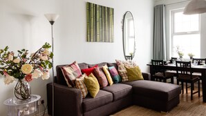 A modern living room with a sectional sofa, a dining table, and a large window.