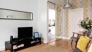 A living room with a black entertainment unit, a large mirror, and a dining area with a chair and a table.