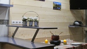 A kitchen with wooden walls, a flat-screen TV, a small table with candles, and a painting of a sunset. - Comfortable studio just a stone's throw from the slopes, perfect for skiers! - 1 bedroom (Les Belleville)