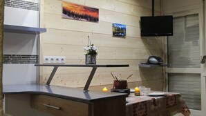 A modern kitchen with wooden panel walls, a built-in bench, a flat-screen TV, and a small dining table with candles. - Comfortable studio just a stone's throw from the slopes, perfect for skiers! - 1 bedroom (Les Belleville)