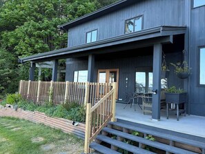 A modern two-story house with a covered porch, a wooden fence, and a garden area. - Oceanfront French Beach 1 king bedroom firepit (Shirley)