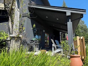 A modern house with a covered porch, a grill, and a chair. - Oceanfront French Beach 1 king bedroom firepit (Shirley)