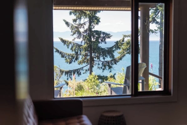 A room with a window overlooking a tree and a body of water.