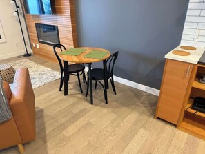 Uma cozinha moderna com uma mesa redonda, duas cadeiras, um armário de madeira e um forno embutido.