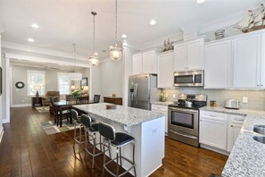 Enjoy cooking in this well-equipped kitchen with a central island, stainless steel appliances, and white cabinetry.