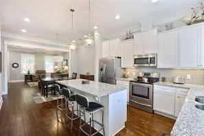 Enjoy cooking in this well-equipped kitchen with a central island, stainless steel appliances, and white cabinetry.