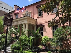 Traditional building with a classic portico and lush gardens, home to a restaurant.
