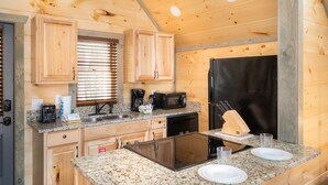 A compact kitchen with wooden cabinets, a black refrigerator, a microwave, a toaster, and a sink.