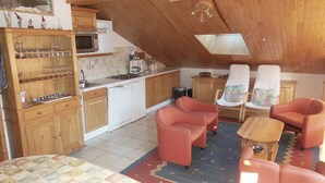 Ein gemütliches Schlafzimmer im Dachgeschoss mit Küchenzeile, Holzmöbeln und einem gemusterten Teppich.