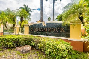 A sign for 'The Shambock' with a landscaped entrance featuring palm trees and a stone pathway. - Charming Kendall Home in Miami (Miami)