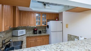 A compact kitchen with wooden cabinets, a white refrigerator, a microwave, a coffee maker, and a sink. - Charming Kendall Home in Miami (Miami)