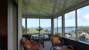 A covered patio with wicker furniture, a table, and a vase.