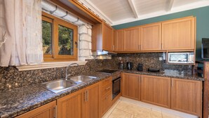 A kitchen with granite countertops, wooden cabinets, a built-in oven, and a window with curtains.