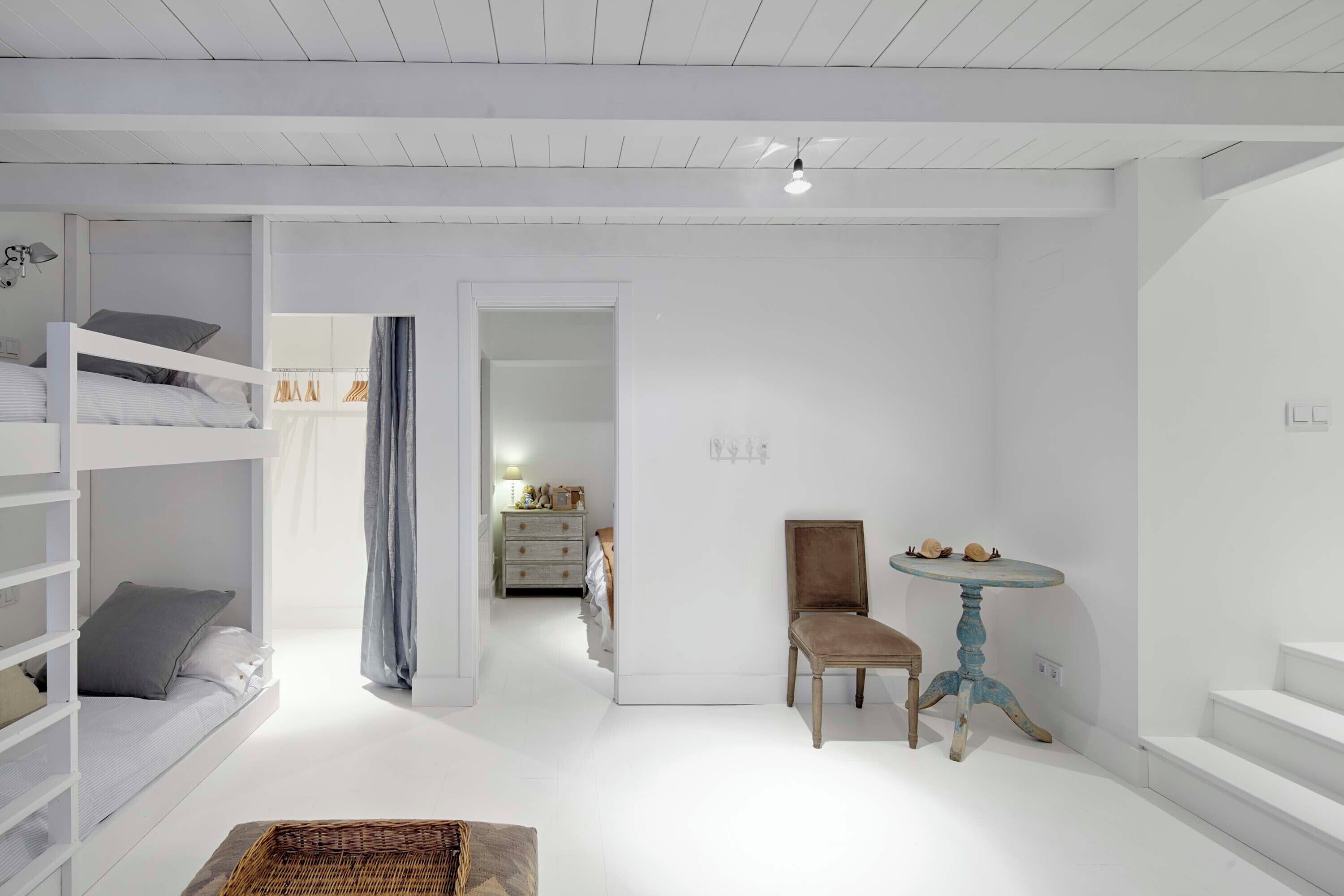 A minimalist room with bunk beds, a small table, and a chair.