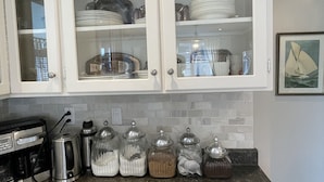 Una cocina con armarios blancos, encimera de granito y diversos electrodomésticos.