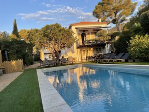 Un área de piscina con sillas de descanso y un edificio con balcón al fondo.