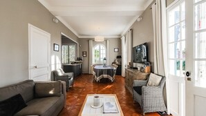 Een ruime woonkamer met een bank, een eettafel en een televisie.