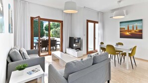 Un soggiorno moderno con un divano, un tavolino, una TV e un'area da pranzo con sedie gialle.