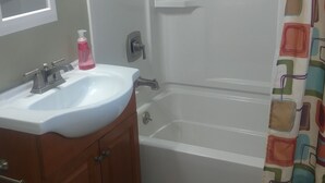 Une salle de bain avec un lavabo blanc, un miroir et un rideau de douche.