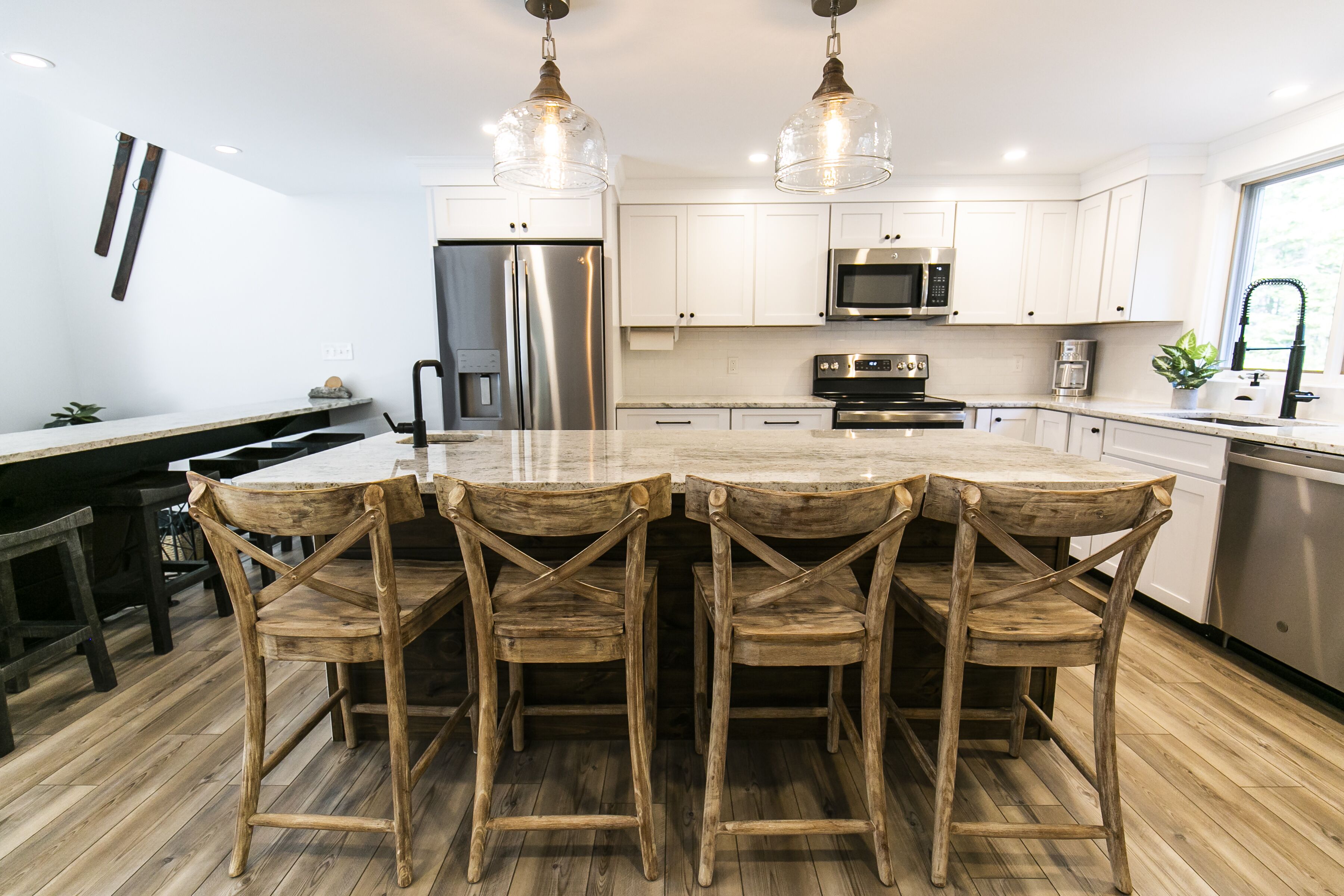 A modern kitchen with white cabinets, stainless steel appliances, and a wooden dining table with four chairs.