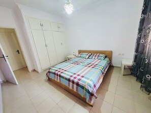 Une chambre à coucher avec un lit, une armoire, une table de chevet et un rideau.