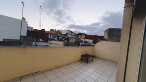 Una terraza en la azotea con suelo de baldosas, una mesita y una silla.