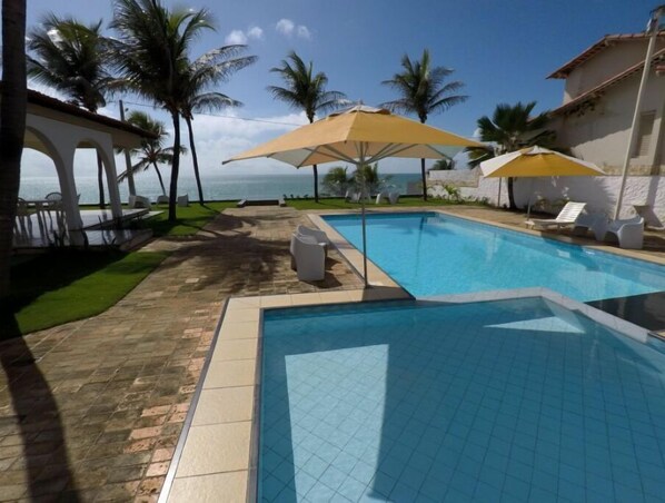 Relax by the oceanfront pool surrounded by palm trees and lounge chairs.
