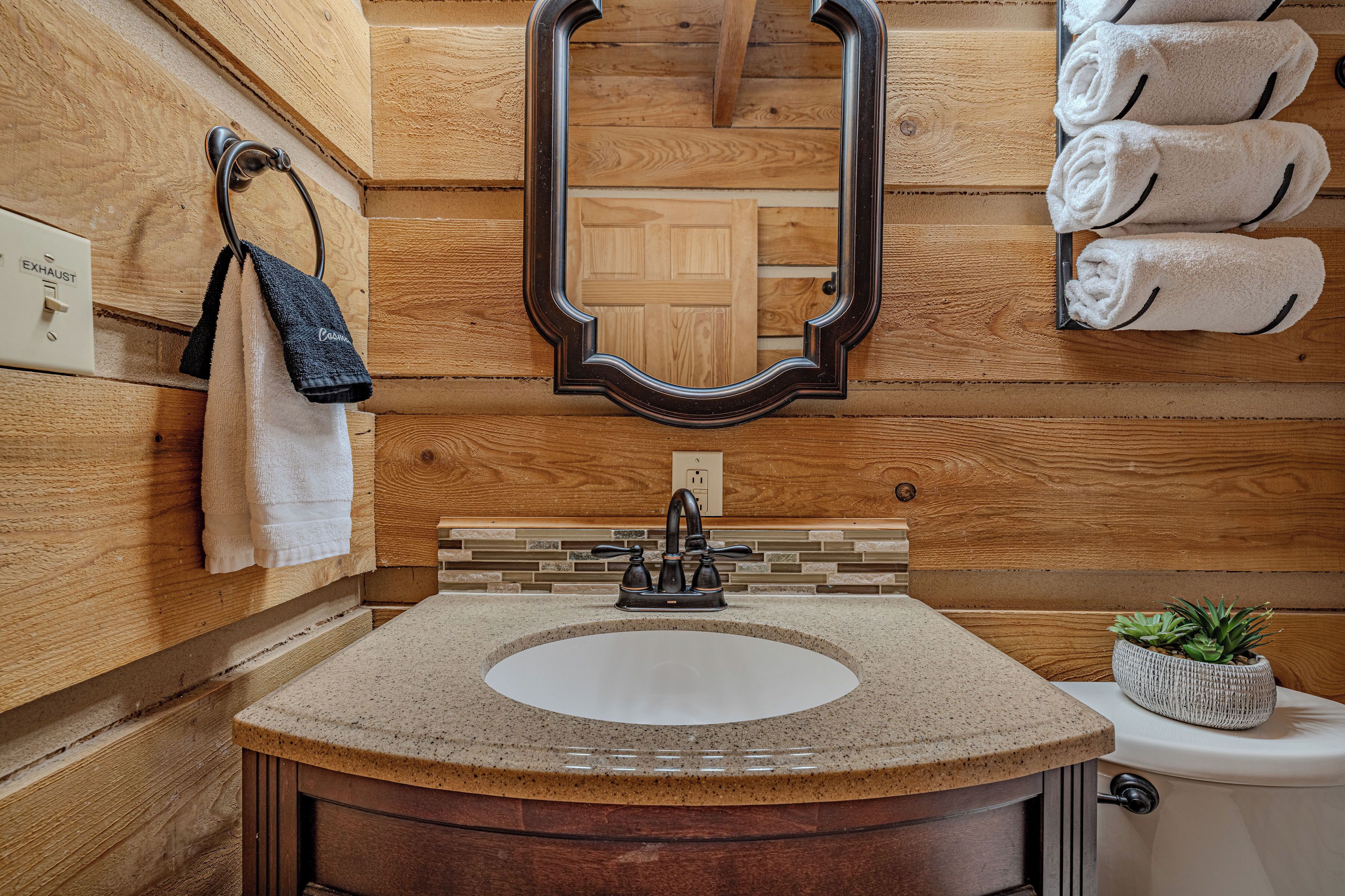 Un baño de estilo cabaña de madera con un lavabo redondo, un espejo y un perchero para toallas.